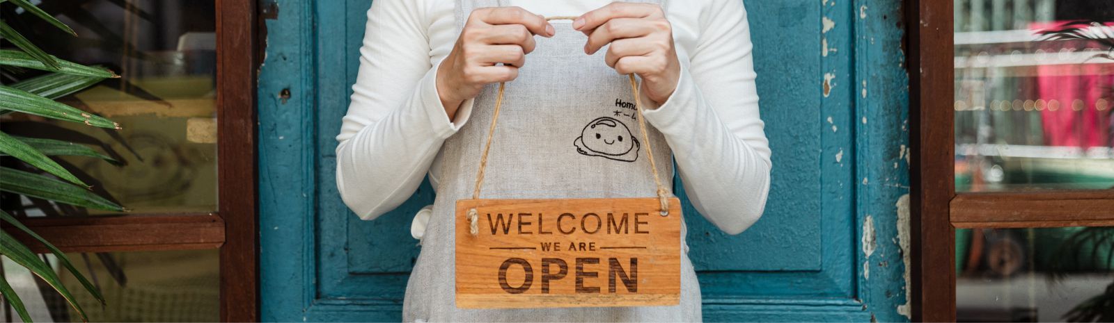 Woman holding a Welcome We're Open sign.