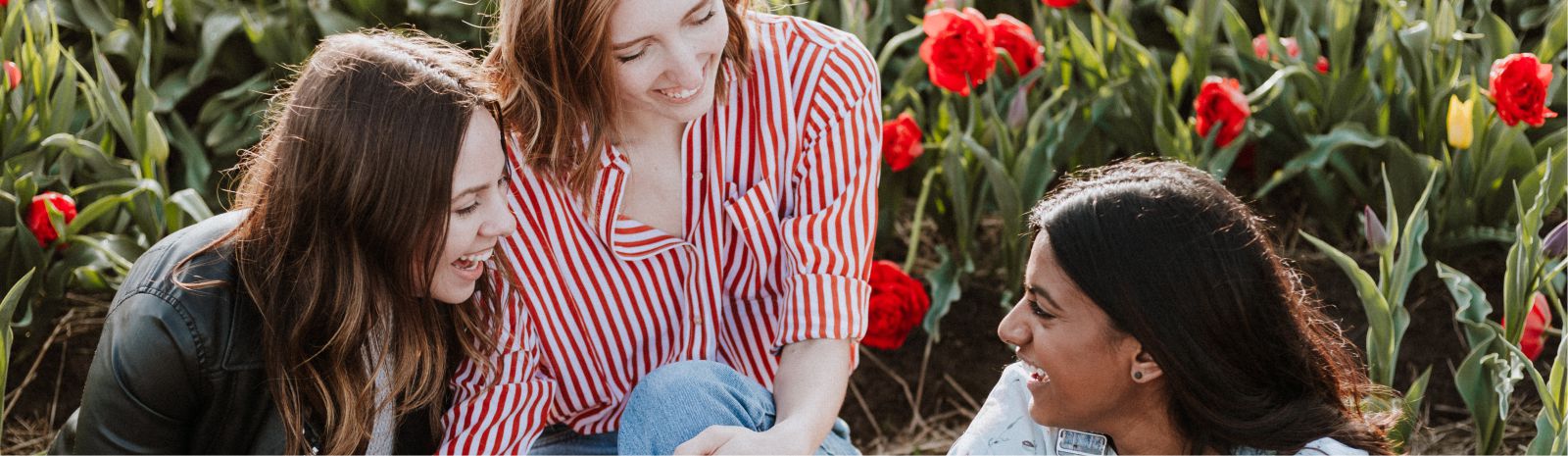 3 teen girls sitting amongst flowers