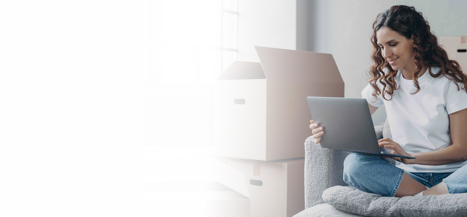 Background image of woman on laptop with cardboard boxes next to her.