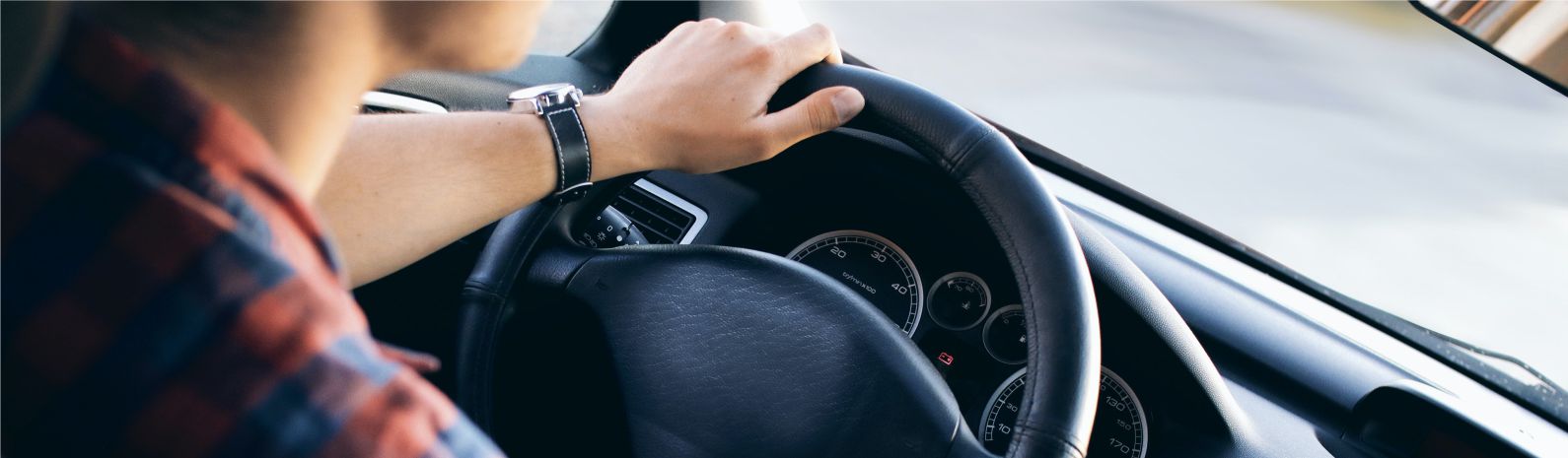 young male with hand on steering wheel