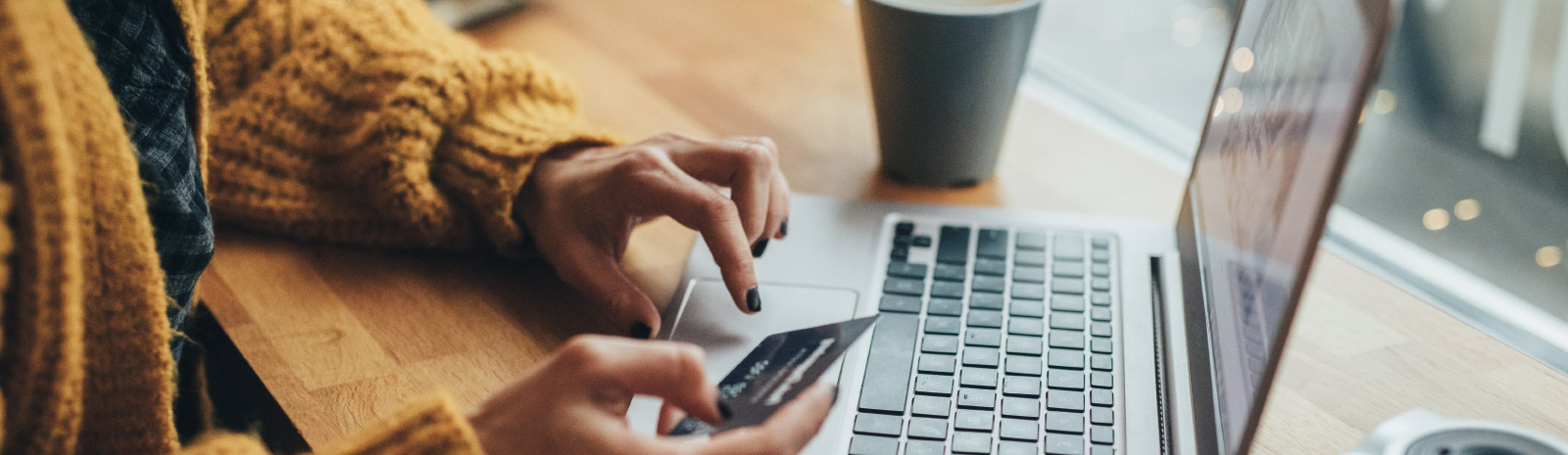 Woman holding a card in hand while typing on computer