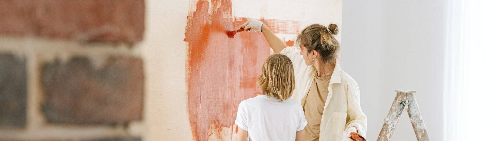 Woman and child painting wall.
