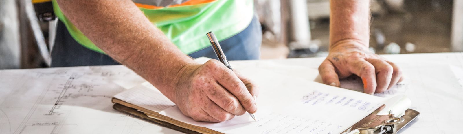 Male construction worker writing on clipboard.