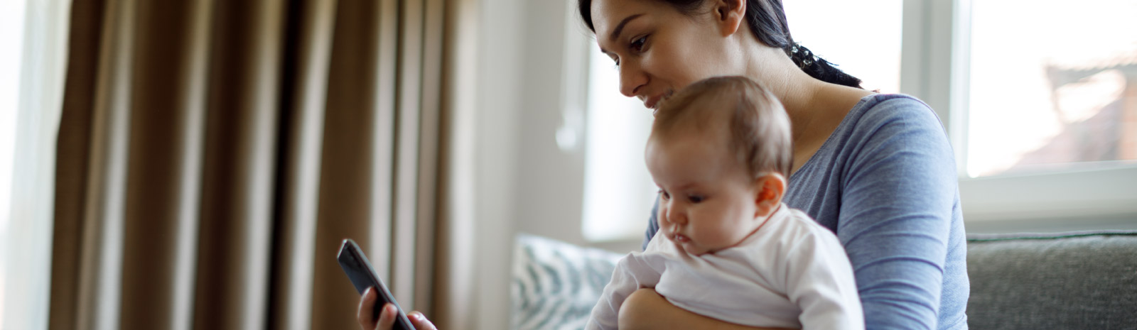 Mother holding baby and phone in home